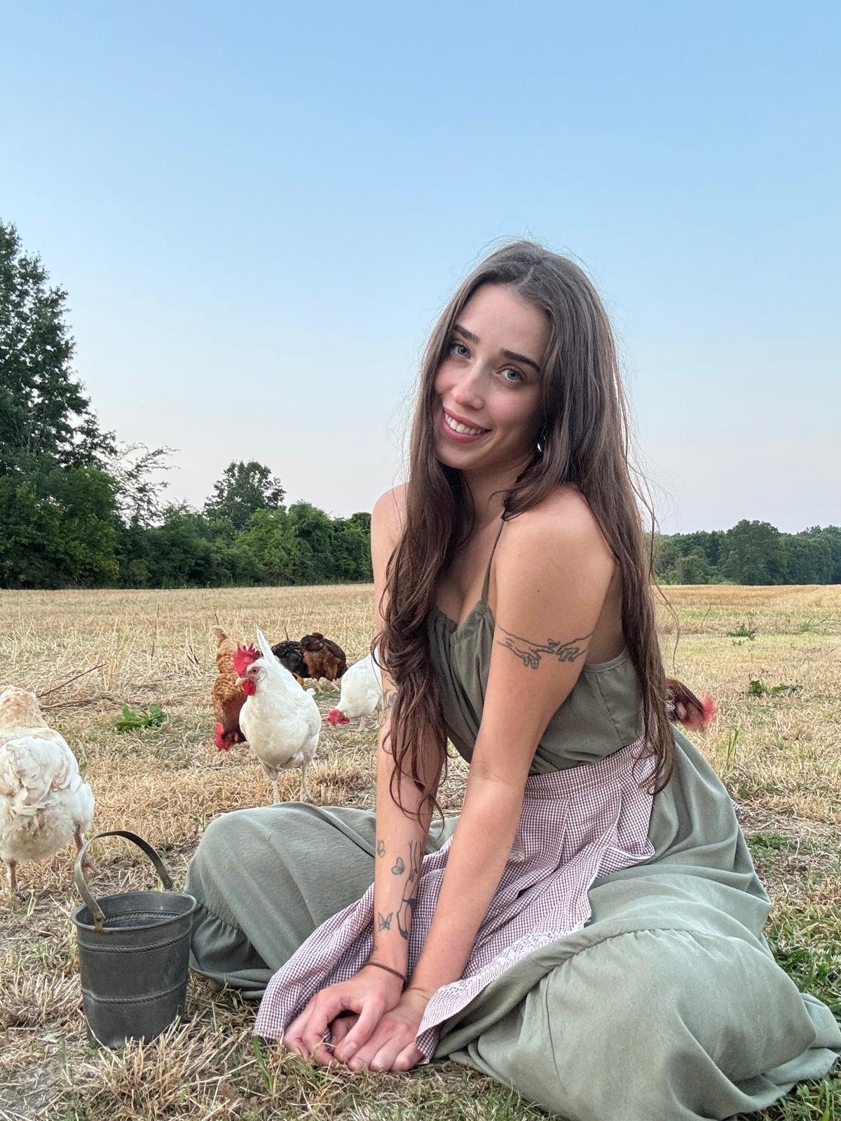 Livinia sitting in a field with her chickens